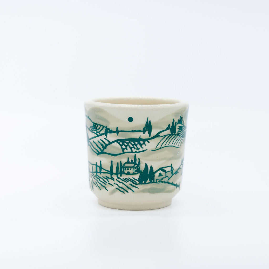 Ceramic cup with green landscape design on a white background