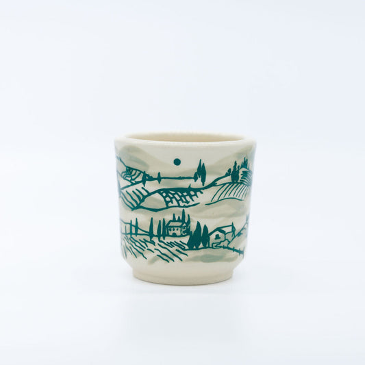 Ceramic cup with green landscape design on a white background